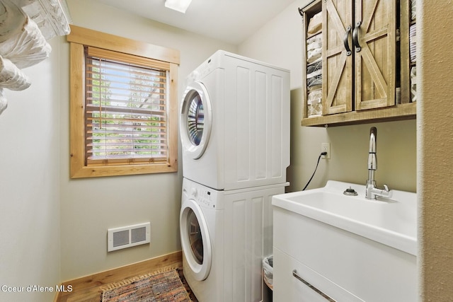 304 Hagman Rd, Nordman, ID 83848 - laundry area featuring stacked washing machine and dryer, cabinet space, wood finished floors, and baseboards