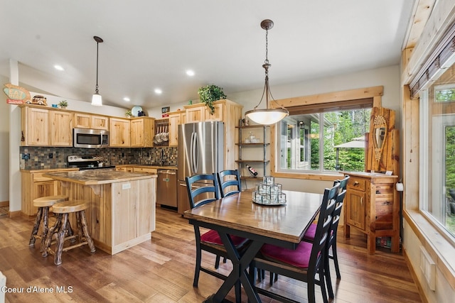 304 Hagman Rd, Nordman, ID 83848 - kitchen with stainless steel appliances, light brown cabinets, a kitchen island, light wood-style flooring, and decorative backsplash