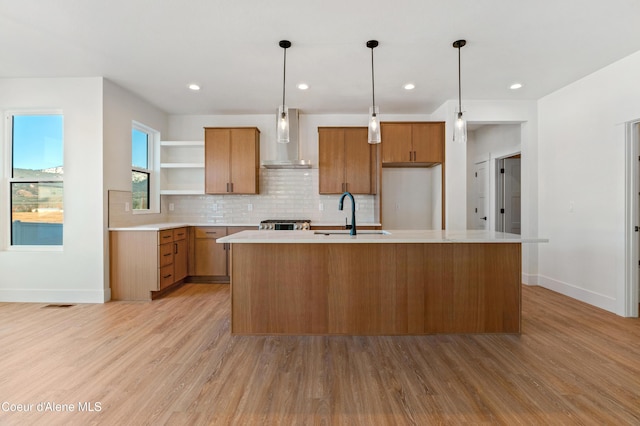 kitchen featuring wall chimney range hood, a sink, open shelves, light wood-type flooring, and light countertops