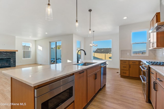 kitchen featuring appliances with stainless steel finishes, a sink, light wood finished floors, a chandelier, and recessed lighting
