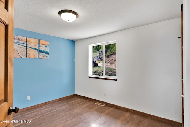 12251 W Blessing Hill Rd, Post Falls, ID 83854 - spare room with wood-type flooring, baseboards, and a textured ceiling