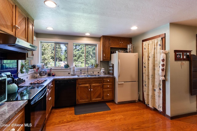 249 Gun Club Rd, Sagle, ID 83860 - kitchen with black appliances, a sink, under cabinet range hood, brown cabinets, and light wood-style flooring
