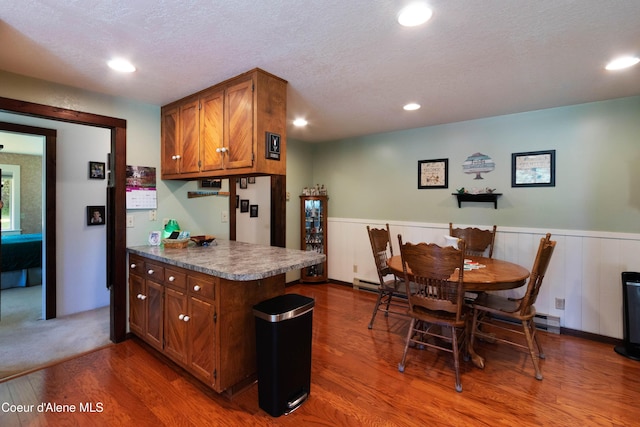 249 Gun Club Rd, Sagle, ID 83860 - kitchen featuring wood finished floors, wainscoting, brown cabinets, a textured ceiling, and recessed lighting