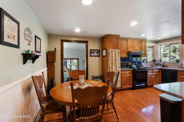 249 Gun Club Rd, Sagle, ID 83860 - kitchen with black appliances, light wood-type flooring, wainscoting, plenty of natural light, and under cabinet range hood