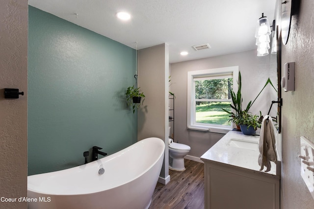 249 Gun Club Rd, Sagle, ID 83860 - bathroom with a textured wall, wood finished floors, vanity, a soaking tub, and toilet