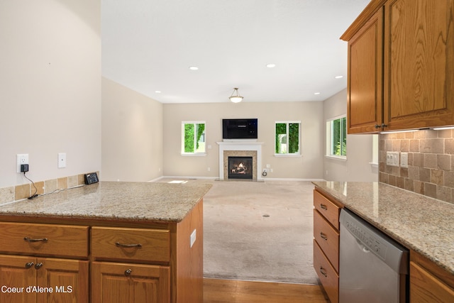 3253 W Magistrate Loop, Hayden, ID 83835 - kitchen featuring stainless steel dishwasher, brown cabinets, a glass covered fireplace, decorative backsplash, and recessed lighting