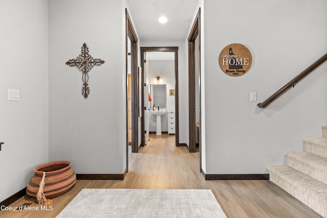 3172 N Cyprus Fox Loop, Post Falls, ID 83854 - hallway with baseboards, light wood-style flooring, stairway, and a sink