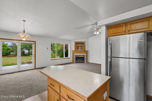 1100 E Autumn Crest Loop, Post Falls, ID 83854 - kitchen with freestanding refrigerator, open floor plan, a glass covered fireplace, a center island, and light countertops