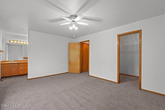 1100 E Autumn Crest Loop, Post Falls, ID 83854 - unfurnished bedroom featuring a sink, carpet, baseboards, a walk in closet, and connected bathroom