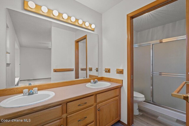 1100 E Autumn Crest Loop, Post Falls, ID 83854 - bathroom with toilet, a shower stall, wood finished floors, and double vanity