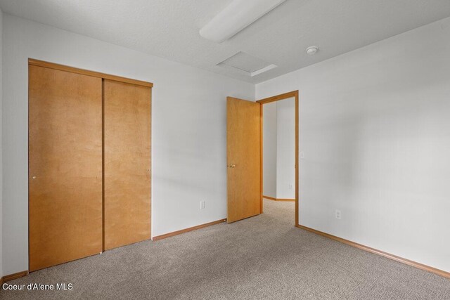 1100 E Autumn Crest Loop, Post Falls, ID 83854 - unfurnished bedroom with carpet flooring, attic access, baseboards, and a closet