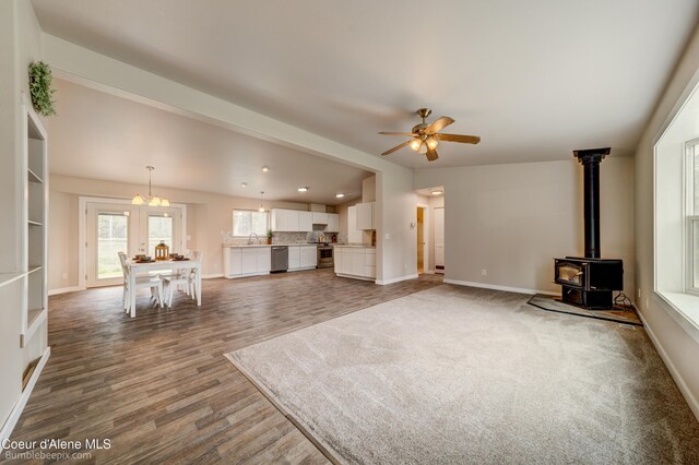 30603 N Riffle Rd, Spirit Lake, ID 83869 - unfurnished living room with a wood stove, baseboards, a sink, ceiling fan, and wood finished floors