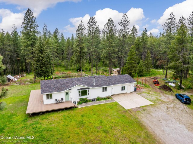 30603 N Riffle Rd, Spirit Lake, ID 83869 - rear view of house featuring driveway, a wooden deck, a lawn, and a wooded view
