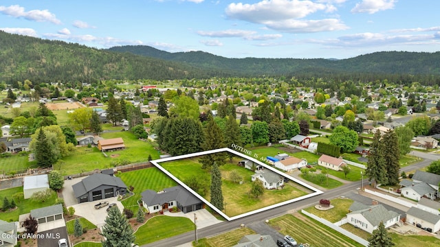 aerial view of residential area with property parcel outlined, mountains, and a heavily wooded area