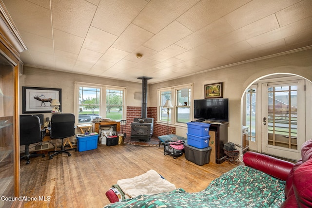living area featuring wood finished floors, a wood stove, healthy amount of natural light, and crown molding