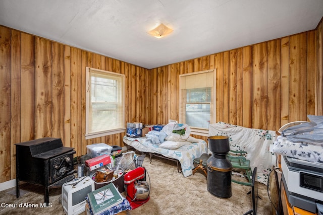 living room featuring wood walls, a wood stove, and carpet flooring