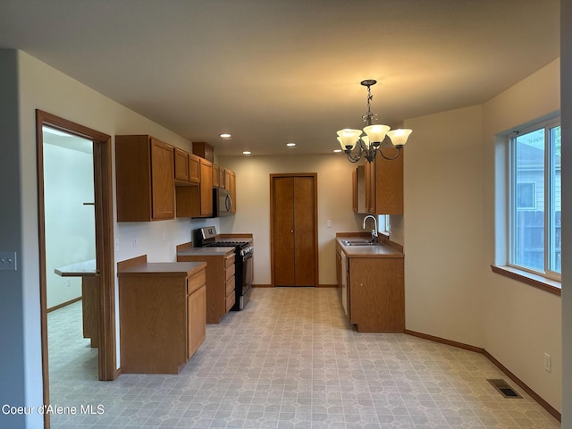 1205 Kinnikinnik Ave, Sandpoint, ID 83864 - kitchen featuring gas range oven, stainless steel microwave, a chandelier, brown cabinets, and recessed lighting