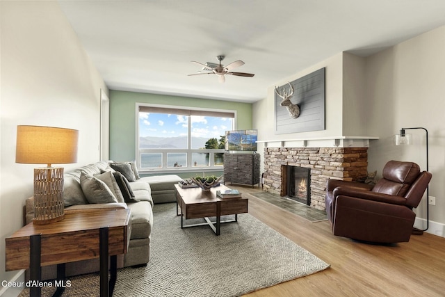 living area featuring wood finished floors, a ceiling fan, and a fireplace
