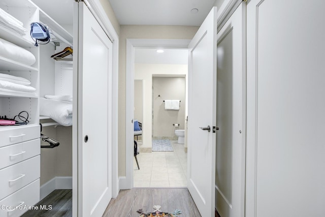 hallway featuring light wood-style flooring and baseboards