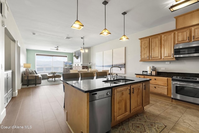 kitchen featuring stainless steel appliances, a sink, open floor plan, a kitchen island with sink, and ceiling fan