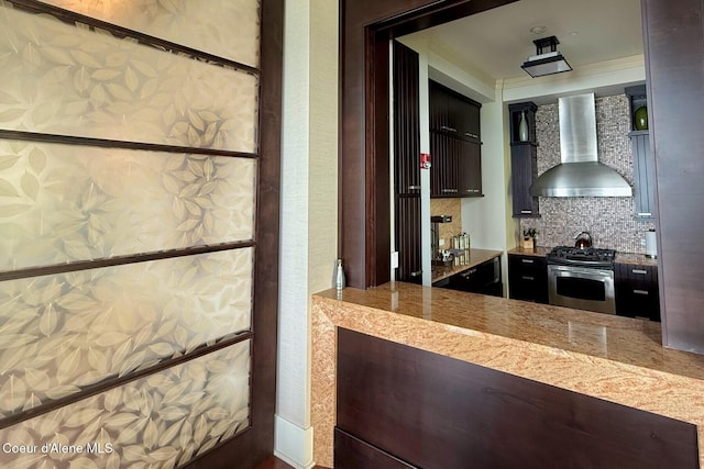 kitchen featuring wall chimney exhaust hood, stainless steel range with gas cooktop, and backsplash