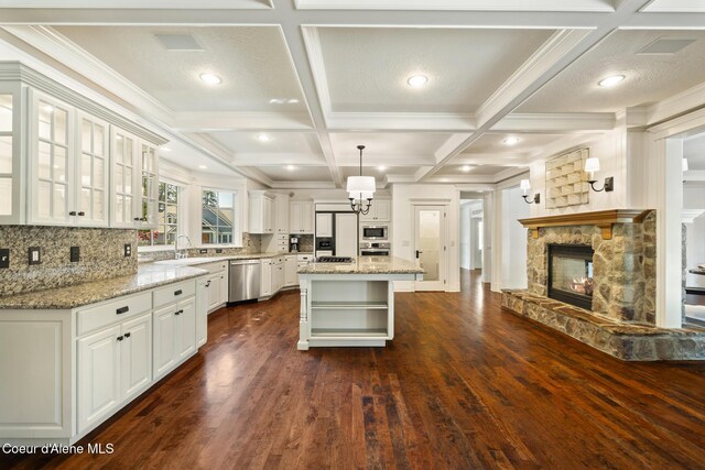 2484 E Woodstone Dr, Hayden, ID 83835 - kitchen with stainless steel appliances, open shelves, a stone fireplace, light stone countertops, and coffered ceiling
