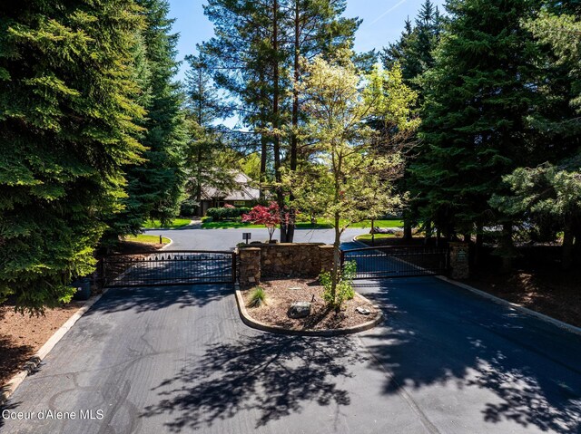 2484 E Woodstone Dr, Hayden, ID 83835 - view of asphalt road featuring a gate, curbs, and a gated entry