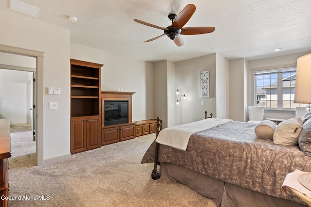 4445 W Greenchain Loop Unit 2, Coeur Dalene, ID 83814 - bedroom with carpet, a textured ceiling, a glass covered fireplace, and a ceiling fan