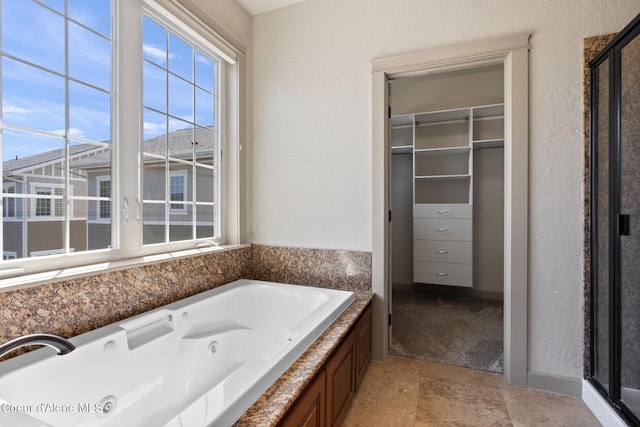 4445 W Greenchain Loop Unit 2, Coeur Dalene, ID 83814 - full bathroom featuring a walk in closet, a tub with jets, and a shower stall