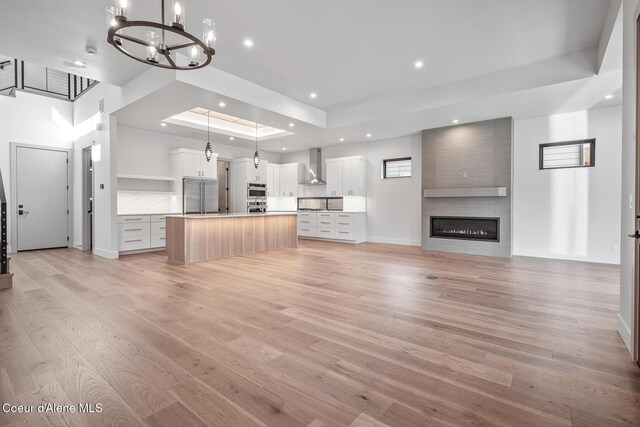 2867 W Lumber Ln, Coeur Dalene, ID 83814 - unfurnished living room with a tray ceiling, light wood-style floors, a fireplace, a chandelier, and recessed lighting