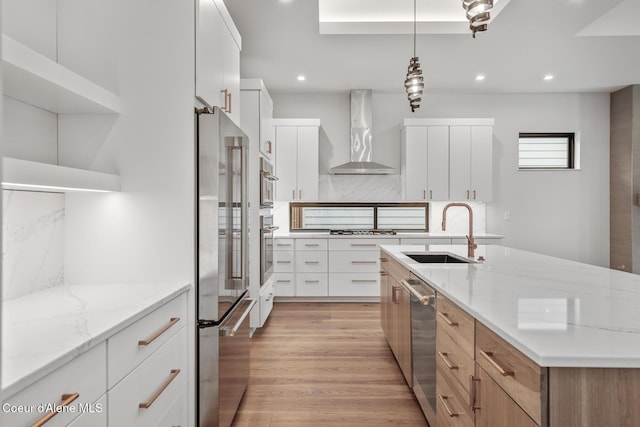 2867 W Lumber Ln, Coeur Dalene, ID 83814 - kitchen with wall chimney exhaust hood, a sink, stainless steel appliances, light wood-type flooring, and decorative backsplash