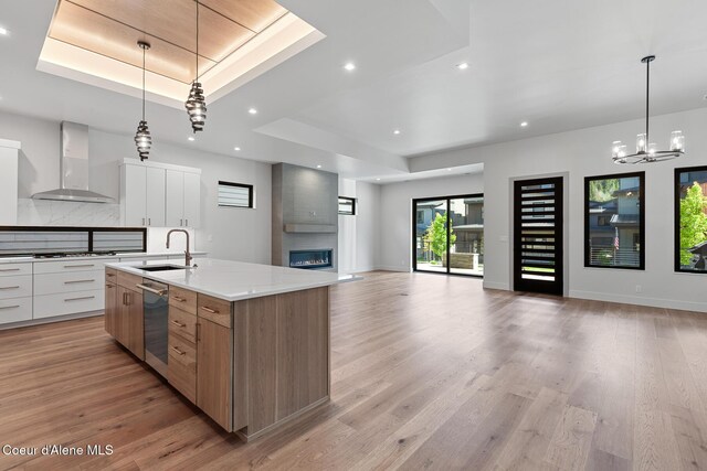 2867 W Lumber Ln, Coeur Dalene, ID 83814 - kitchen with a tray ceiling, wall chimney range hood, modern cabinets, a sink, and recessed lighting