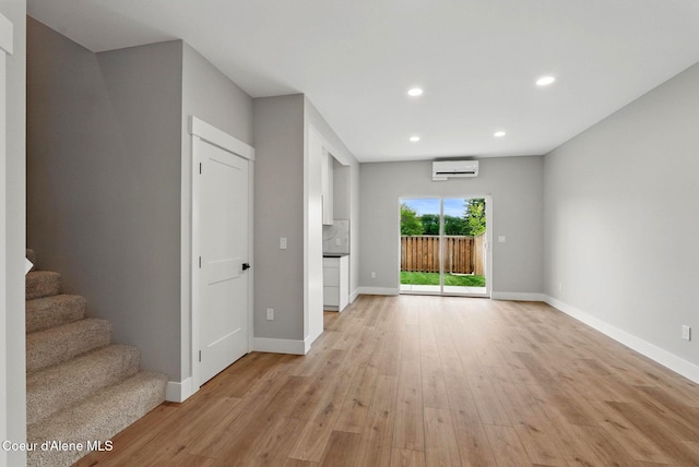 1678 Onyx Ct, Sandpoint, ID 83864 - unfurnished living room featuring a wall mounted AC, light wood-type flooring, baseboards, recessed lighting, and stairway