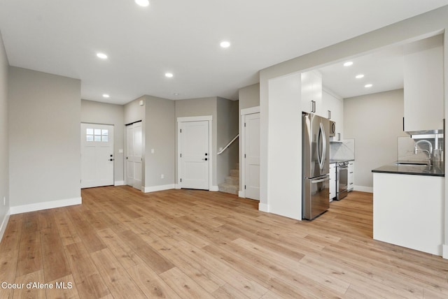 1678 Onyx Ct, Sandpoint, ID 83864 - unfurnished living room with a sink, stairs, light wood finished floors, baseboards, and recessed lighting