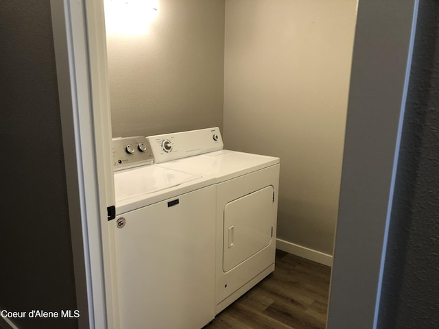 clothes washing area with separate washer and dryer and dark wood-style flooring