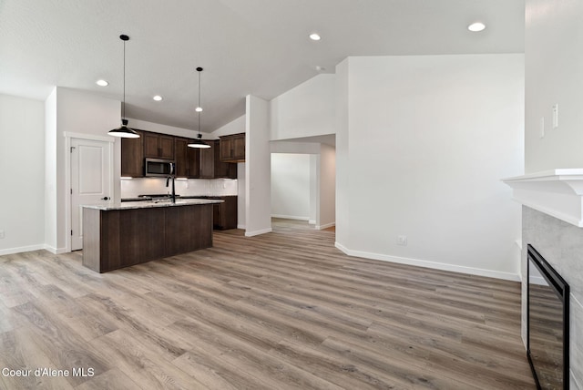 7823 N Girard Cir, Coeur Dalene, ID 83815 - kitchen with stainless steel microwave, an island with sink, dark brown cabinets, baseboards, and recessed lighting