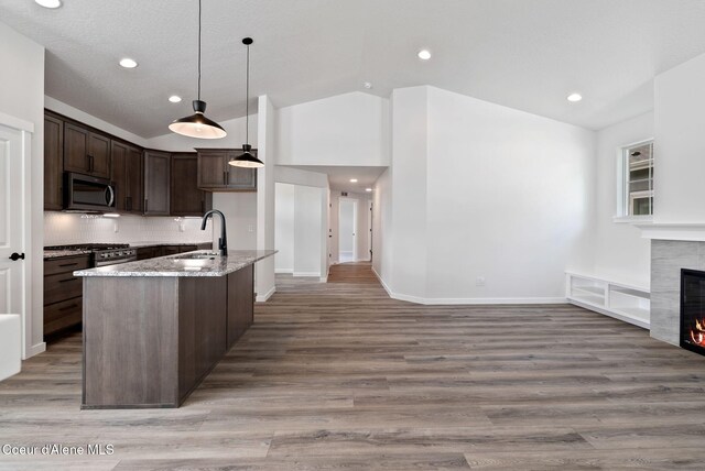 7823 N Girard Cir, Coeur Dalene, ID 83815 - kitchen with stainless steel microwave, a sink, vaulted ceiling, open floor plan, and light stone counters
