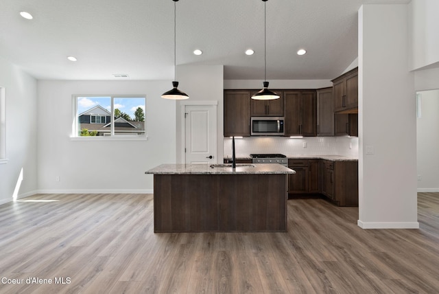 7823 N Girard Cir, Coeur Dalene, ID 83815 - kitchen with stainless steel microwave, stove, tasteful backsplash, a sink, and light wood-style floors