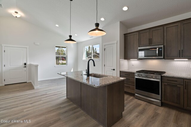 7823 N Girard Cir, Coeur Dalene, ID 83815 - kitchen with appliances with stainless steel finishes, a sink, decorative backsplash, vaulted ceiling, and light stone countertops