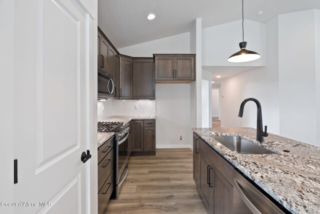 7823 N Girard Cir, Coeur Dalene, ID 83815 - kitchen with appliances with stainless steel finishes, a sink, light wood-type flooring, dark brown cabinets, and light stone countertops