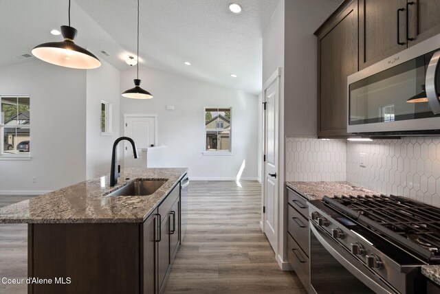 7823 N Girard Cir, Coeur Dalene, ID 83815 - kitchen featuring a sink, appliances with stainless steel finishes, vaulted ceiling, dark brown cabinets, and backsplash