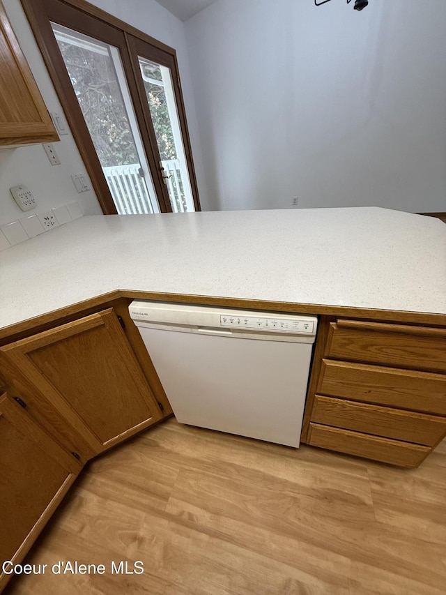 5188 E Woodland Dr, Post Falls, ID 83854 - kitchen featuring dishwasher, light wood-style floors, a peninsula, and brown cabinets