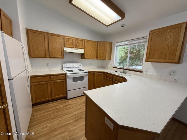 5188 E Woodland Dr, Post Falls, ID 83854 - kitchen with white appliances, a peninsula, under cabinet range hood, lofted ceiling, and brown cabinets