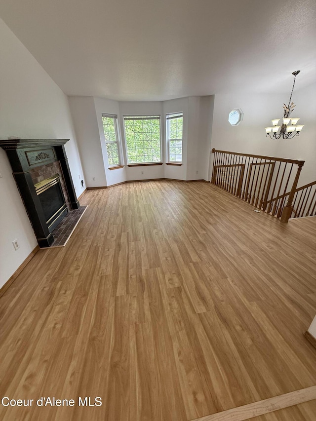 5188 E Woodland Dr, Post Falls, ID 83854 - unfurnished living room with light wood-type flooring, a chandelier, and a fireplace