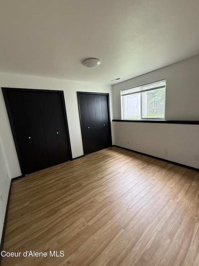 5188 E Woodland Dr, Post Falls, ID 83854 - unfurnished bedroom featuring wood finished floors and two closets