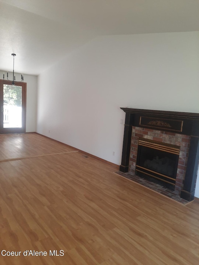 5188 E Woodland Dr, Post Falls, ID 83854 - unfurnished living room featuring light wood finished floors, a brick fireplace, and lofted ceiling