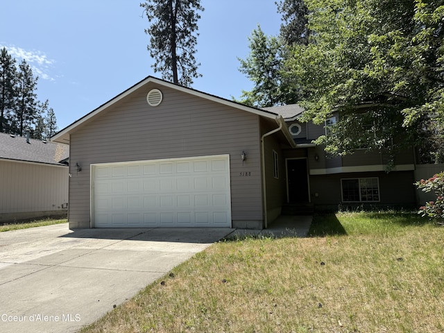 5188 E Woodland Dr, Post Falls, ID 83854 - view of front of home featuring an attached garage, concrete driveway, and a front lawn
