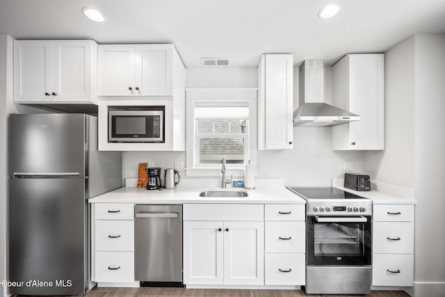 215 W Foster Ave, Coeur Dalene, ID 83814 - kitchen with stainless steel appliances, a sink, wall chimney exhaust hood, white cabinetry, and recessed lighting