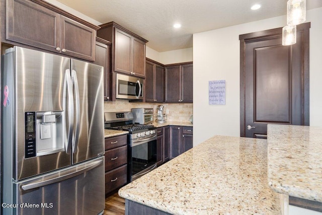 4631 E Alopex Ln, Post Falls, ID 83854 - kitchen featuring stainless steel appliances, dark brown cabinetry, backsplash, light stone counters, and recessed lighting