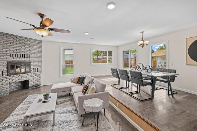 living room with a chandelier, a brick fireplace, baseboards, and ceiling fan